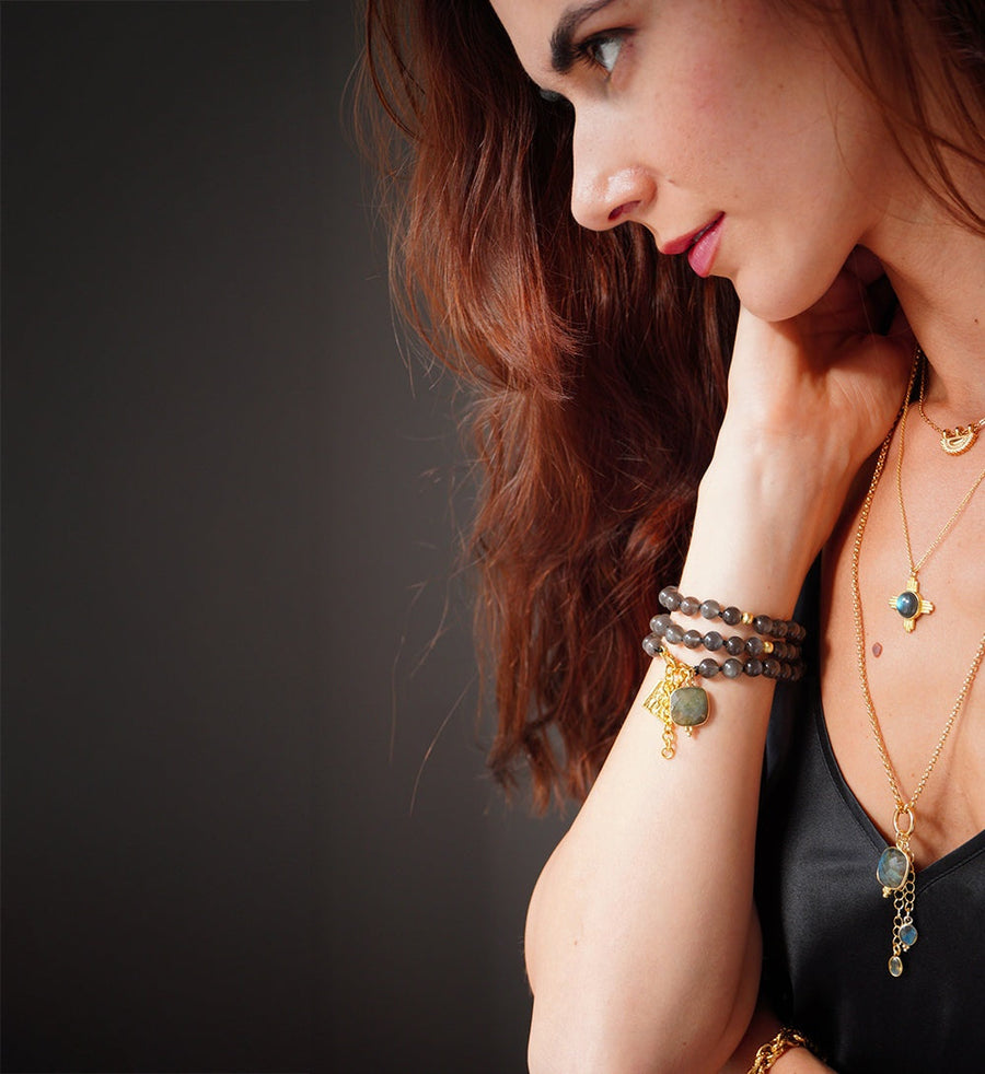 Frau trägt Silent Moon Wickelarmband aus schwarzem Mondstein mit Labradorit-Anhänger am Handgelenk