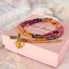 Soul Garden' Turmalin Wickelarmband mit goldfarbenem Bienen-Charm auf rosa Schachtel.